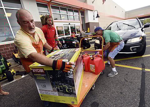 Jim Craig, David Burke and Chris Rayner load generators as people buy supplies at The Home Depot. (Photo | AP)