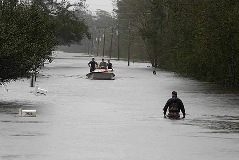 A member of the U.S. Coast Guard walks down Mill Creek Road checking houses after tropical storm Florence hit Newport N.C. (AP)