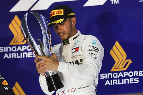 Mercedes driver Lewis Hamilton of Britain holds his trophy as he celebrates after winning the Singapore Formula One Grand Prix at the Marina Bay City Circuit in Singapore. | AP