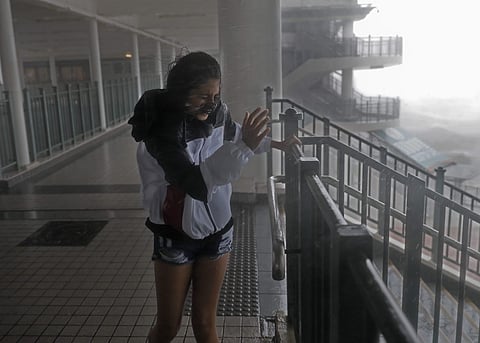 A girl stands against strong wind caused by Typhoon Mangkhut at a pier on the waterfront of Victoria Habour Hong Kong. (AP)