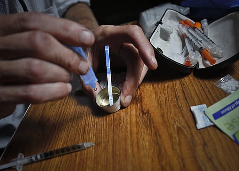 An addict prepares heroin, placing a fentanyl test strip into the mixing container to check for contamination. (Photo | AP)