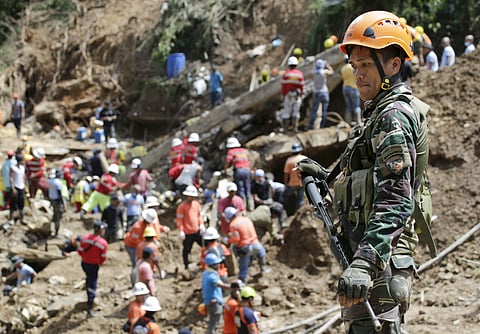 A Filipino trooper keeps guard as search operations continue at the site where victims are believed to have been buried by a landslide triggered by Typhoon Mangkhut lashed across Itogon, Benguet province, northern Philippines, Tuesday, Sept. 18, 2018. (Ph
