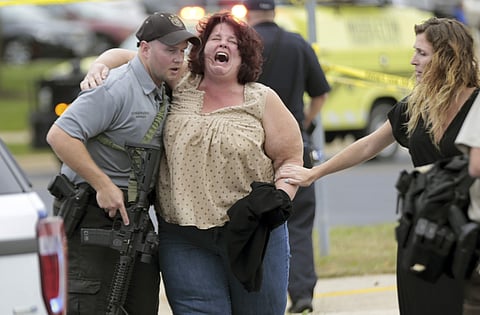 A woman is escorted from the scene of a shooting at a software company in Middleton. (Photo | AP)
