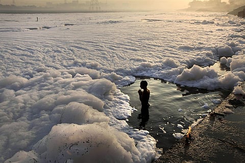 A devotee bathes amidst industrial waste, Shri Yamuna, a tributary of Ganga, New Delhi. (Photo | Associated Press)