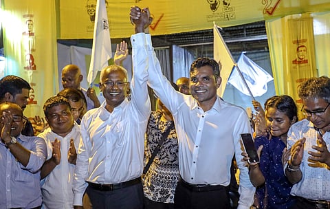 In this early Monday, Sept. 24, 2018 photo, Maldives' opposition presidential candidate Ibrahim Mohamed Solih, third left, and his running mate Faisal Naseem, third right, pose for photographers as they celebrate their victory in the presidential election