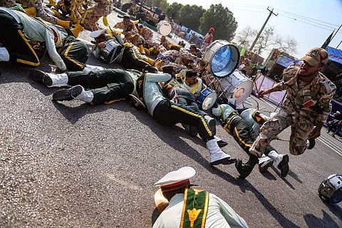 This picture taken on September 22, 2018 in the southwestern Iranian city of Ahvaz shows a soldier running past injured comrades lying on the ground at the scene of an attack on a military parade that was marking the anniversary of the outbreak of its dev