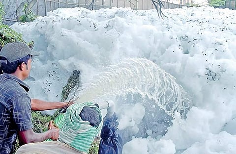 Worker clearing froth that was formed after Tuesday’s heavy downpour at Bellandur lake in Bengaluru | PANDARINATH B