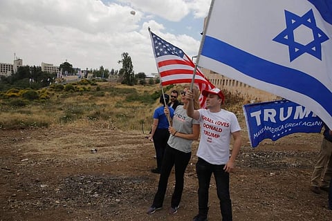 Israelis hold American and Israeli flags with the new US embassy in the background in Jerusalem. (Photo | AP)