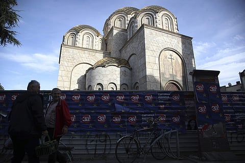 Two men stand in front of an Orthodox church as the banners read 'For European Macedonia' in Skopje. (Photo | AP)