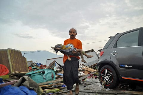 A man carries the body of a child who was killed in the tsunami in Palu, Central Sulawesi, Indonesia, Saturday, Sept. 29, 2018.