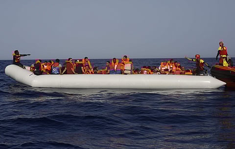 An Open Arms lifeguard gives a thumbs-up to a migrant at the other end of a rubber boat in the middle of a rescue operation. (Photo | AP)
