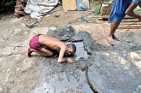 File photo of a manual scavenger cleaning a sewer by hand