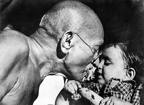 Gandhiji seen here playing with a tot.