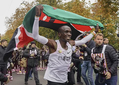 Eliud Kipchoge celebrates with the Kenyan flag after breaking the historic two hour barrier for a marathon in Vienna. (Photo | AP)