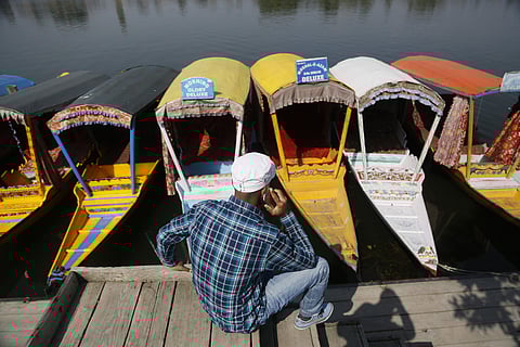 A Kashmiri boatman talks on his cellphone as he sits on the banks of the Dal Lake in Srinagar on Monday, Oct. 14, 2019. (Photo | AP)