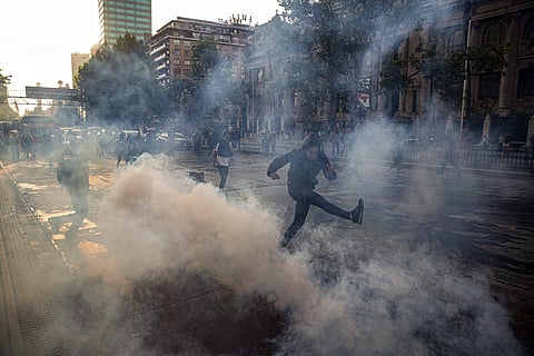 A protester kicks a tear gas canister launched by police near the Santa Lucia subway station during a protest against the rising cost of subway and bus fares. | ( Photo | AP )