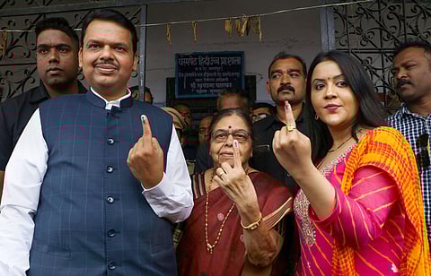 Maharashtra CM Devendra Fadnavis casts his vote along with his wife Amruta and mother Sarita at a polling booth in Nagpur. (Photo | PTI)