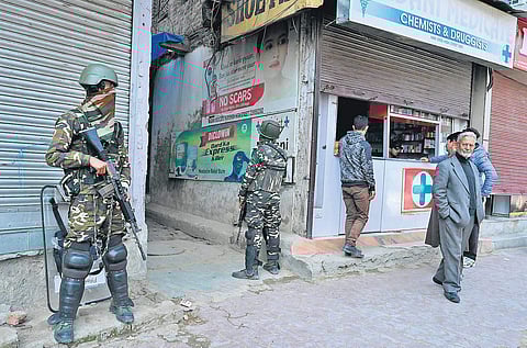 Troopers stand guard outside a chemist in Srinagar. Security has been enhanced a day after two men were killed in Kashmir (Photo| PTI)