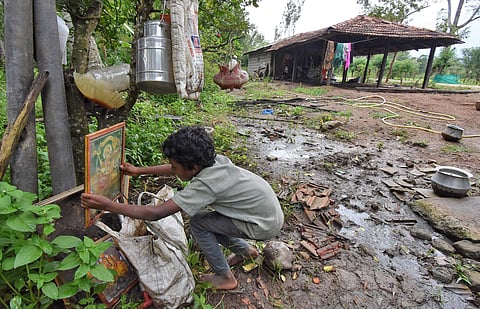 A boy places a portrait of Goddess Chamundeshwari in front of his damaged house in Konasahalli in Hunsur. (Photo | Udayshankar S, EPS)