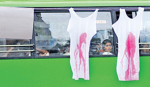 Commuters inside a bus look at the dresses hung by protesters seeking justice for Walayar sisters at Vanchi Square in Kochi on Wednesday | A Sanesh