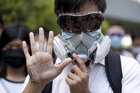 A protester wears a gas mask and holds up his hand to represent the protester's five demands in Hong Kong. (Photo | AP)