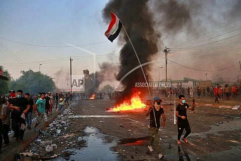 Anti-government protesters set fires and close a street during a demonstration in Baghdad, Iraq. (Photo | AP)