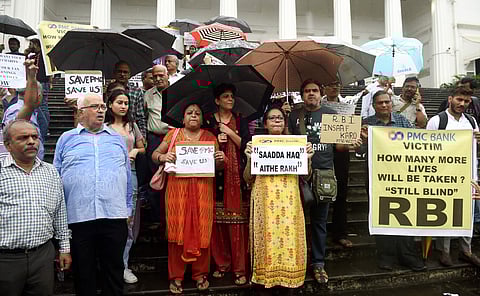 Depositors of the PMC bank display placards during a protest over the RBI 's curb at RBI headquarters in Mumbai. (File Photo | PTI)