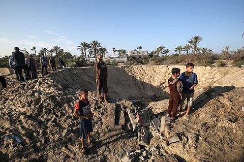 Palestinian children stand around a crater caused by an Israeli airstrike launched in response to rocket fire, in Khan Yunis in the southern Gaza Strip on November 2, 2019. (Photo | AFP)