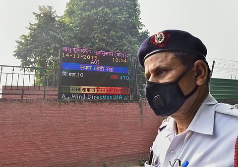 A traffic policeman wearing an anti-pollution mask stands next to a digital board displaying Air Quality Index on the compound wall of a weather observatory at Lodhi Road in New Delhi Wednesday Nov. 13 2019. | (Photo | PTI)
