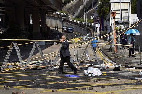 A man crosses in front of a roadblock set up by pro-democracy protesters outside the Hong Kong Baptist University, in Hong Kong, Wednesday. (Photo | AP)