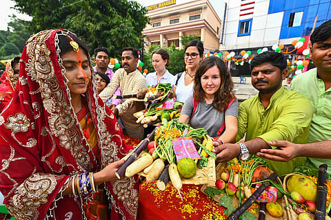 Foreign tourists distribute puja materials on the occasion of Chaath Puja in Bodhgaya. (Photo | PTI)