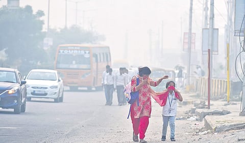 A woman and her daughter cover their faces to protect themselves from the toxic air in New Delhi on Friday. Air quality in the city has been on a free-fall over the last few days. (Photo | PTI )