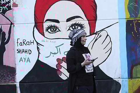 In this Sunday, Nov. 17, 2019 photo, a woman stands in front of graffiti at the Saadoun Tunnel, in Baghdad, Iraq. (Photo | AP)