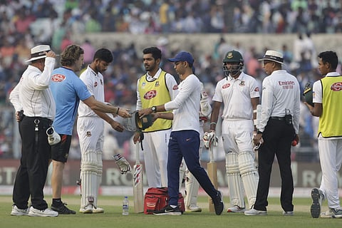 Bangladesh's Nayeem Hasan, third left, stands as physiotherapists of India and Bangladesh look into the helmet after he was injured by a delivery by India's Mohammed Shami. (Photo | AP)