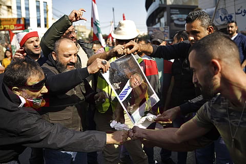 Demonstrators burn a photograph of U.S. President Donald Trump during a protest by few dozen people against what they called, 'America's intervention in Lebanon's affairs,' near the U.S. embassy in Aukar, northeast of Beirut, Lebanon, Sunday, Nov. 24, 201
