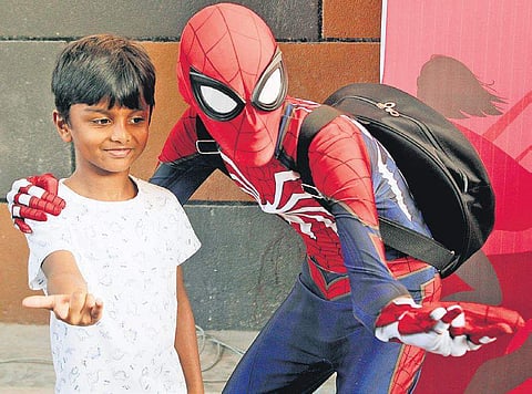 A child poses with a cosplayer dressed as Spiderman. (Photo| ENS)