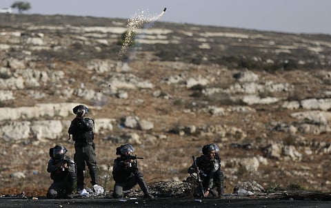 Israeli troops fire teargas as they clash with Palestinians during the protest against the U.S. announcement that it no longer believes Israeli settlements violate international law., at checkpoint Beit El near the West Bank city of Ramallah, Tuesday. (Ph