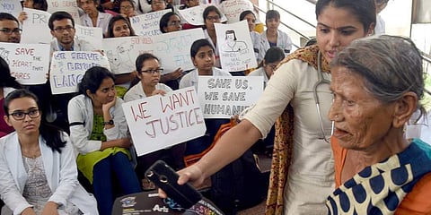 Doctors from Minto Hospital in Bengaluru stage a dharna on Tuesday, while some help patients visiting the hospital.(Photo | Nagaraga Gadekal, EPS)