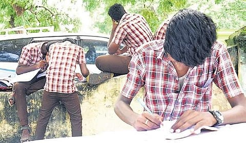 Students writing Thirukkural
