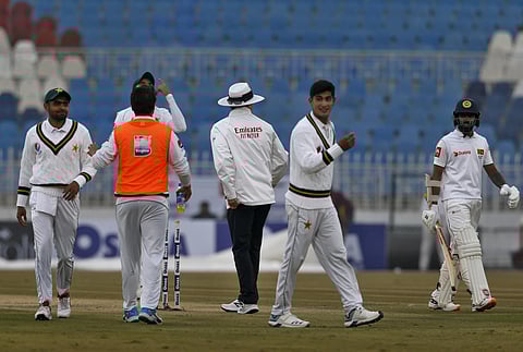 Sri Lankan batsman Niroshan Dickwella (R) and Pakistani players walk back to the pavilion while play stops due to rain during the second-day of the 1st cricket test match between Pakistan and Sri Lanka in Rawalpindi (Photo| AP)