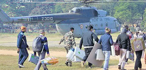Government and security personnel carry poll equipment at a helipad at Hazaribagh in Jharkhand on Wednesday | PTI