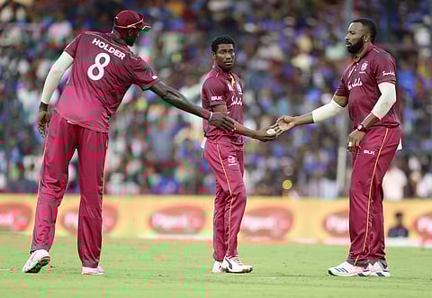 Kieron Pollard hands over the ball to Keemo Paul as Jason Holder looks on. (Photo | AP)