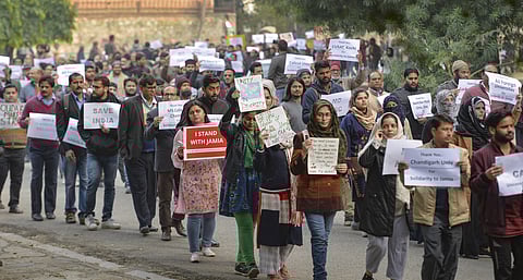 Jamia teachers and staff display placards during a peaceful protest march against the Citizenship Act in New Delhi| PTI