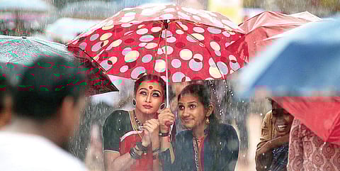 Parvathi Krishna (left) of GHSS Kayyur, and her friend Anjima Aravind, take cover under an umbrella as heavy rain lashes the main venue during the prize distribution ceremony of the State School Arts Festival in Kanhangad on Sunday. Parvathi, daughter of
