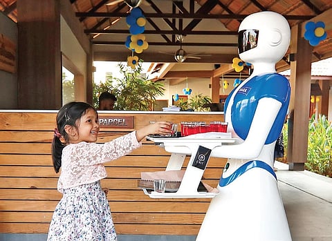 A child is all smiles as a robot greets her at Thakkaram restaurant. (Photo | EPS, Arun Angela)