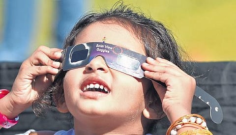 A child watches the annular solar eclipse using special goggles. B P Deepu