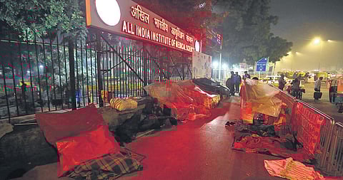 People sleep in the cold on a pavement adjoining the AIIMS hospital in New Delhi on Friday night. (Photo | EPS/Shekhar Yadav)