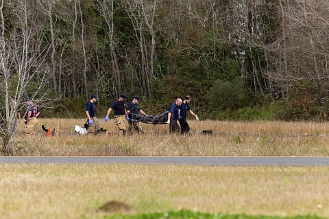 Authorities carry a body bag from the scene after the plane crashed into the parking lot of a post office in Lafayette. (Photo | AP)