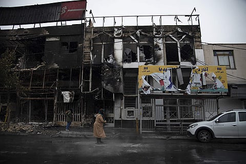 People walk past buildings which burned during protests that followed the authorities' decision to raise gasoline prices, in the city of Karaj, west of the capital Tehran, Iran. (Photo | AP)
