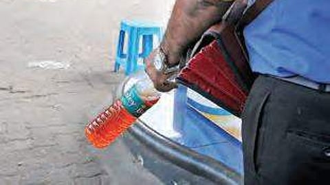 Petrol being bought in a plastic bottle at petrol pump.